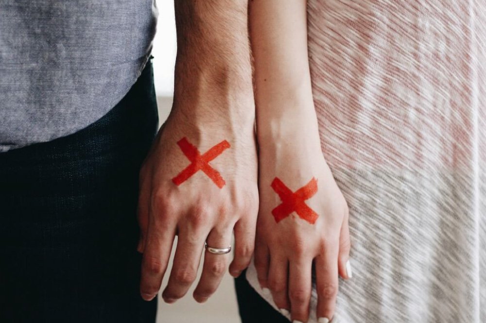 close-up of hands (with a red x on them) of male and female standing next to each other