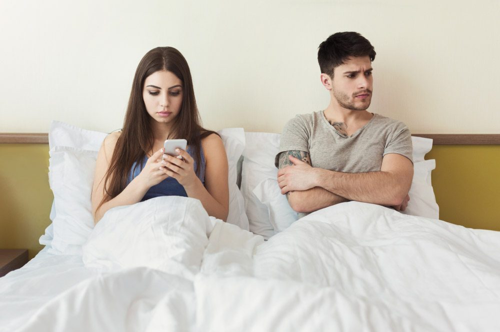 Worried man by his wife smartphone addiction