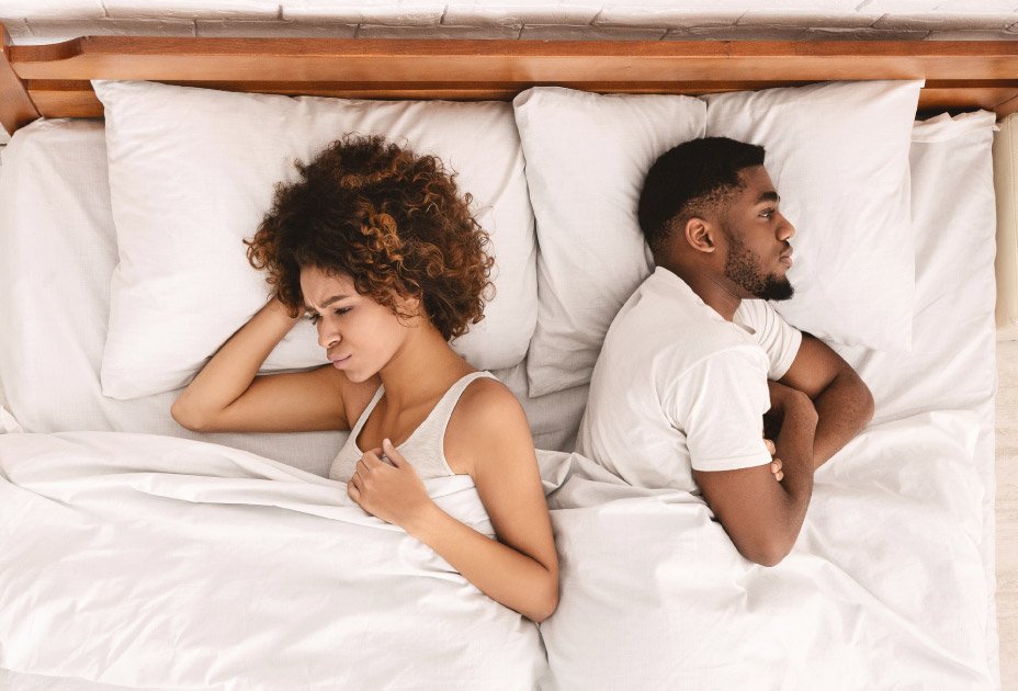 young black couple laying back to back in bed